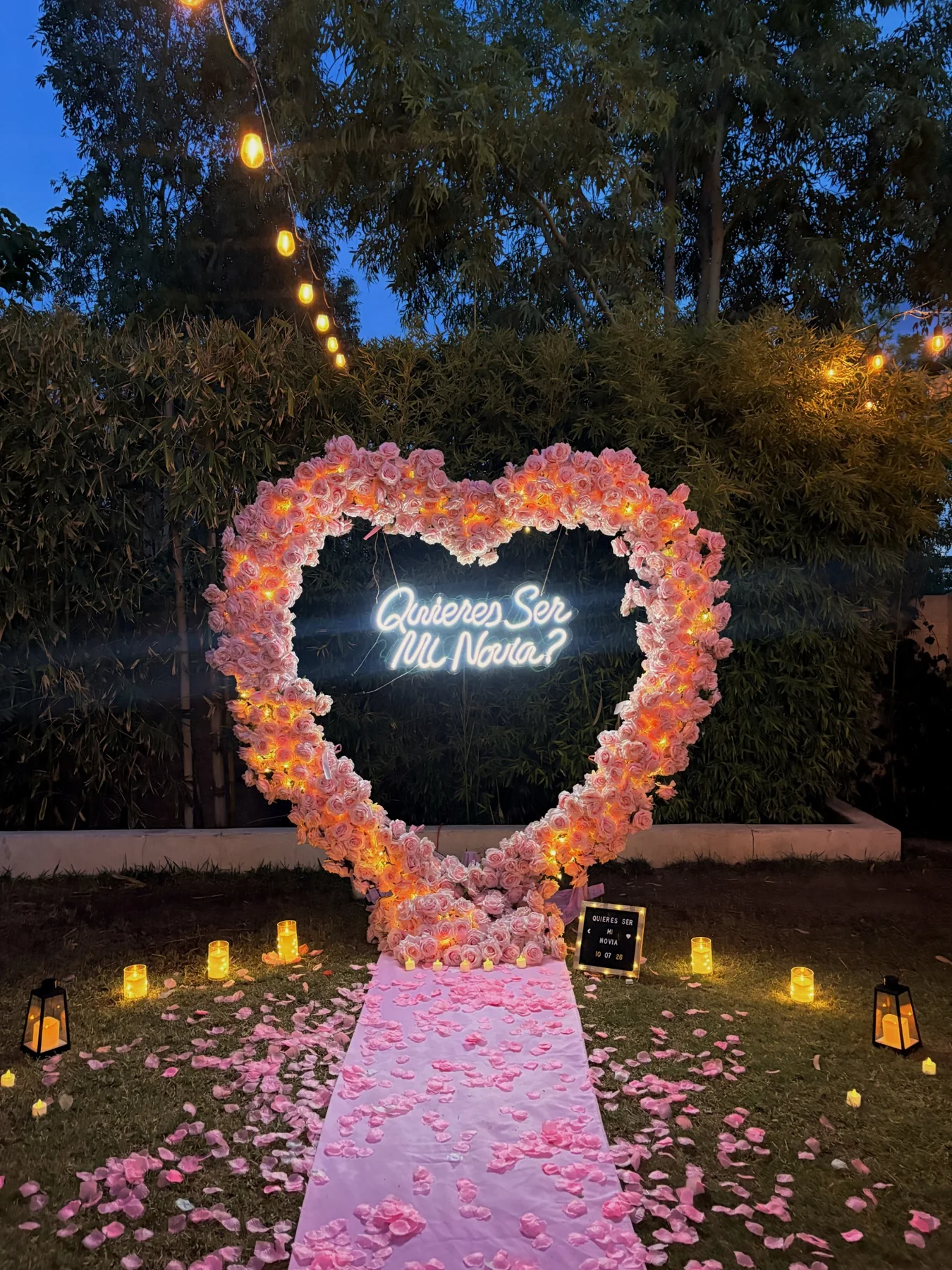 Pedida de noviazgo con corazón floral y camino rosa en jardín